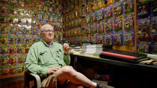 Imagen de Peter Laird en su habitación junto las figuras de Tortugas Ninja