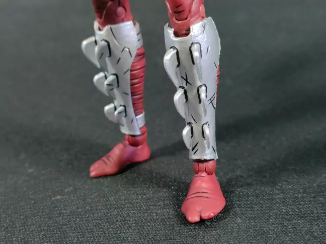 Imagen detalada de las partes metálicas en las piernas de Karai
